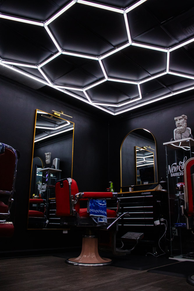 Inside New Edge Barbers, with hexagon ceiling lights, gold-framed mirrors and red barber chairs
