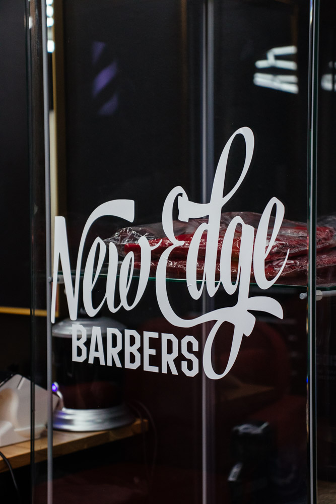 New Edge Barbers script logo on the glass at the shop entrance